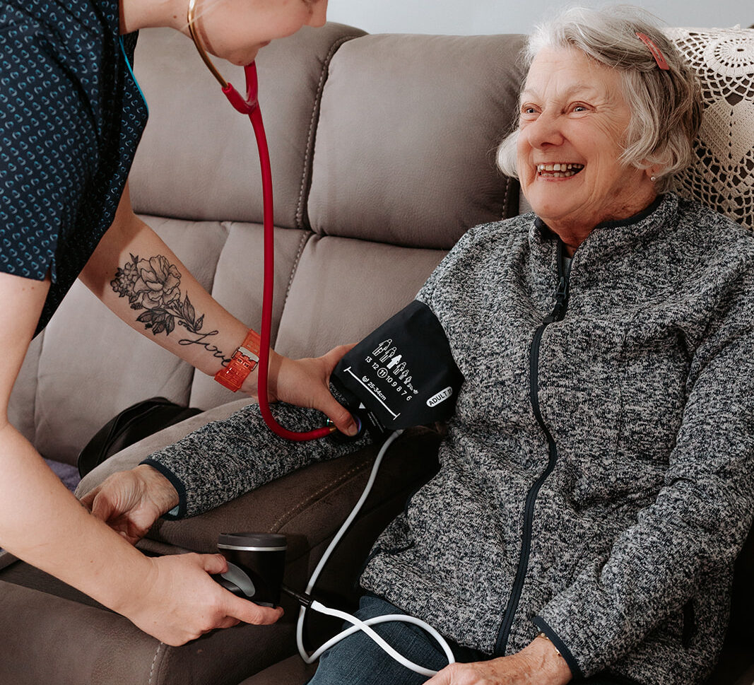 Nurse providing in-home aged care by checking elderly woman’s blood pressure in Portland, Victoria.